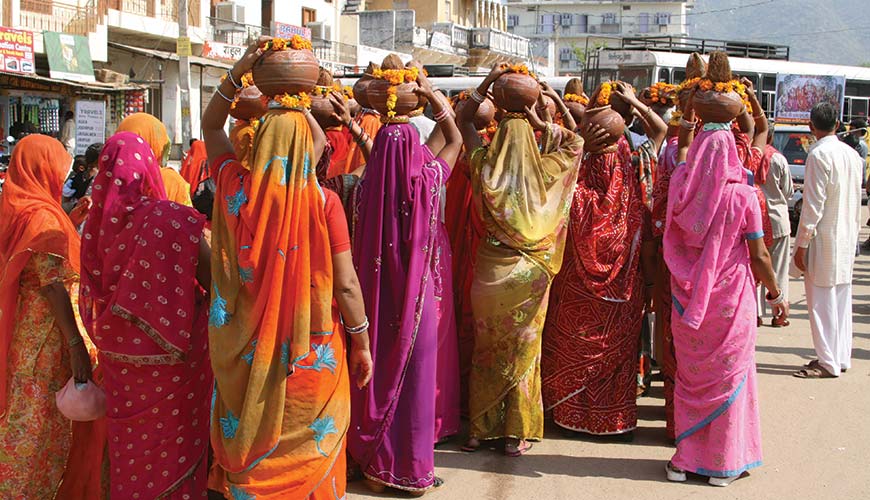 a group of women wearing colourful saris in india walking the streets of delhi