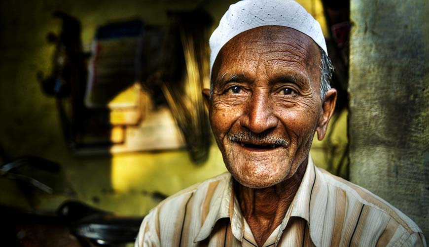 old man smiling in india on the streets of delhi whilst on a group tour