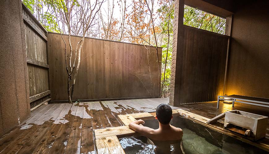 man sitting in an onsen in japan during winter