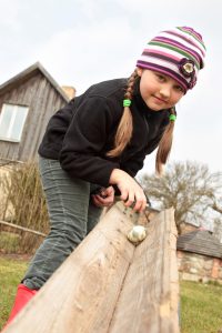 girl rolling egg down a plank of wood at Easter in Britain