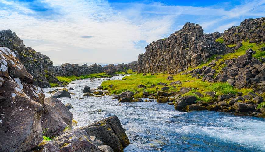 Stream running through green grass and rocks in Thingvellir National Park in Iceland Europe - a setting for a game of thrones location