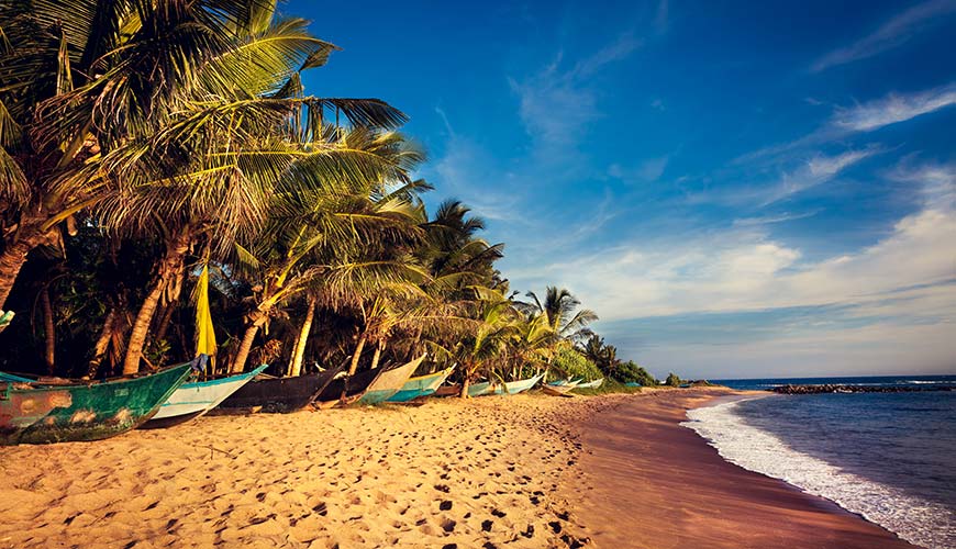 Hikkaduwa beach with boats lining the sand on a holiday to Sri Lanka and Maldives