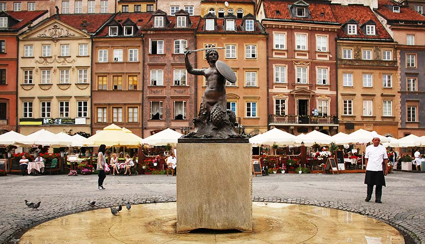 Statue in front of brown coloured buildings in the old town of Krakow in Poland