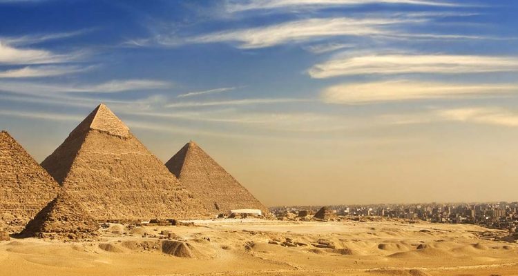 The pyramids in Egypt in the desert with blue skies and clouds