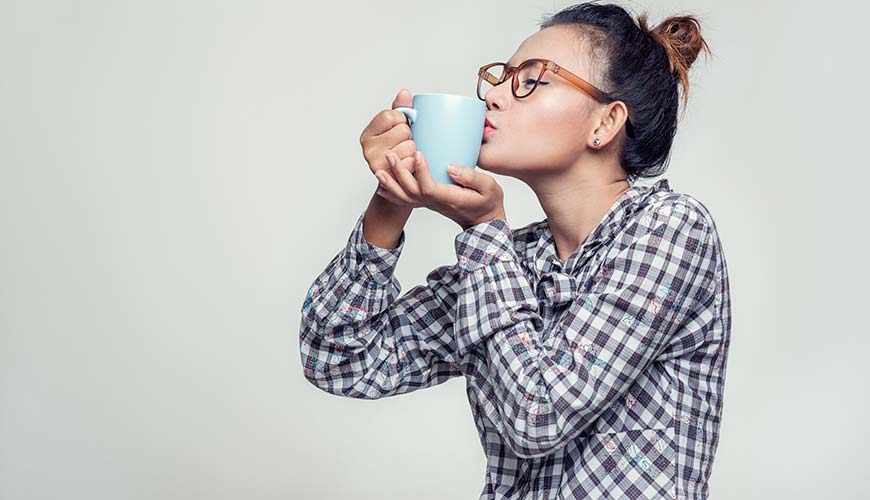 happy woman kissing her morning coffee, save money for travelling