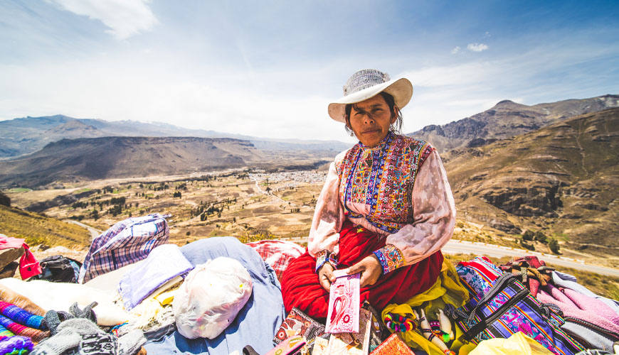 Peruvian Indigenous craft seller with view over a valley