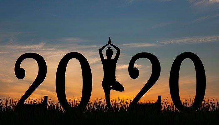 Woman in yoga pose in the middle of 2020 sign on field
