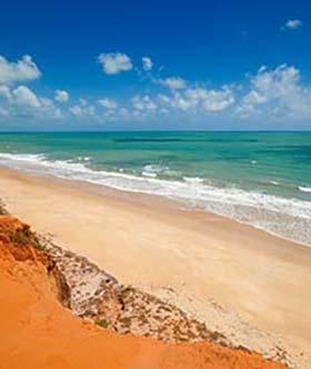 beach with red rock and blue sea in brazil