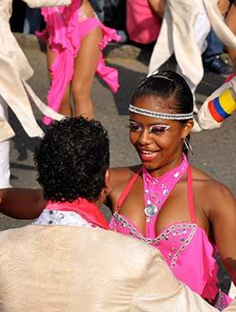 woman wearing pink costume and dancing salsa with a male partner in the street at cali fair in colombia