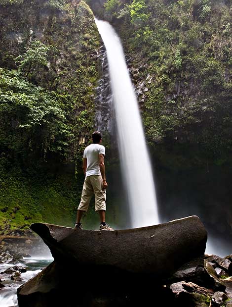 Man standing looking up at La Fortuna Waterfall in Costa Rica