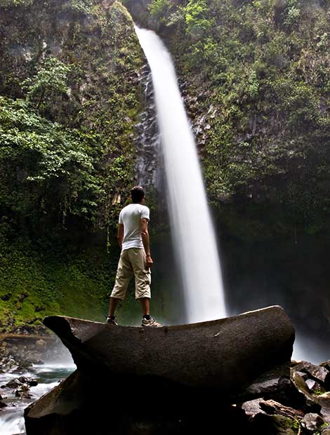 La Fortuna Waterfall in Costa Rica Man standing looking up at La Fortuna Waterfall in Costa Rica