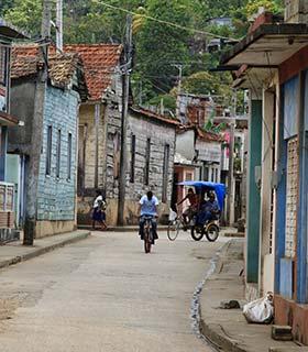 Explore the backstreets of Havana on a tour to Cuba man riding a bike and a rickshaw in the backstreets of havana cuba