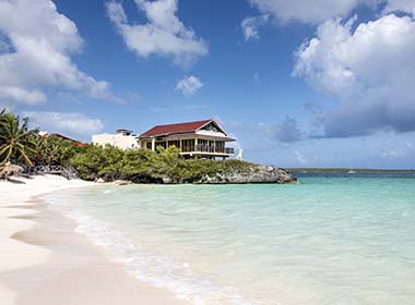 house on a cliff on a beach with white sand and clear seas in maria la gorda cuba