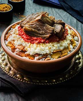 Egyptian food - fettah with rice egyptian food of oriental fettah with white rice and crispy bread topped with seasoned garlic sauce crispy fried garlic and veal chunks on rustic dark background