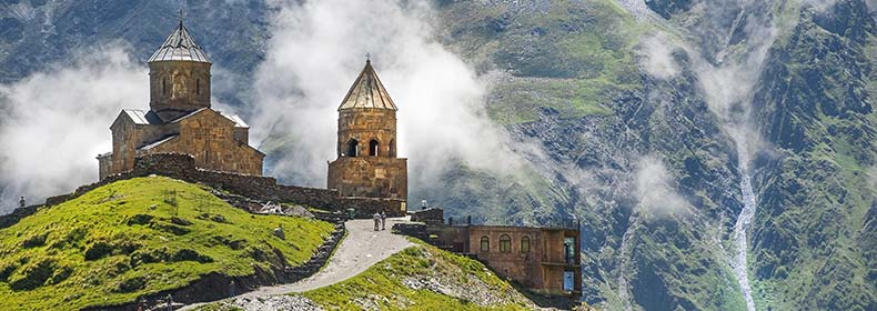 Stepantsminda, Georgia famous Gergeti Trinity Church in Stepantsminda georgia on a hill mountains in the background