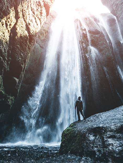 Waterfall in Iceland solo traveller on a group tour in iceland looking up at a powerful waterfall