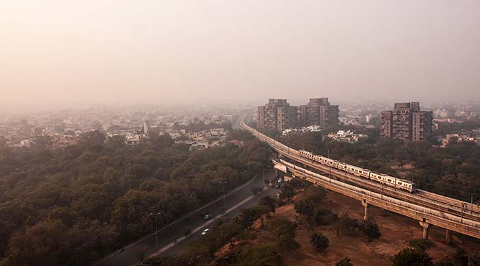 ariel view of new delhi india with train line running towards the dusty city