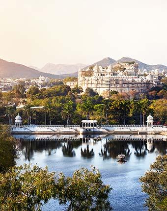 palace on the lake in udaipur india with clear water and green trees surrounding