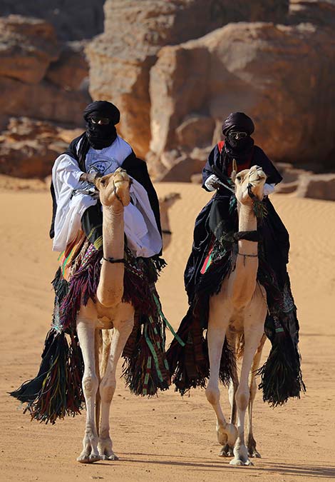 Traditional Bedouin men camel trekking in the Wadi Rum desert bedouin men wearing traditional clothing riding camels in Jordan