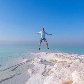 man jumping over salt in the dead sea jordan