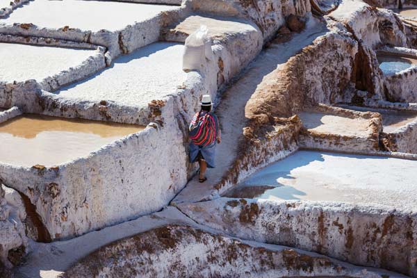 Maras salt ponds tour guides take the group through maras village near the urubamba river as they trek on their holiday trekking adventure