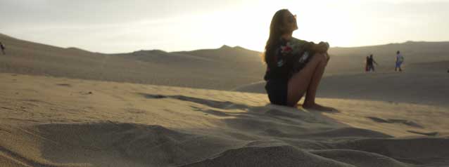 Solo traveller watches sandboarders explore on an excursion the exciting activity sand boarding on the outskirts of lima