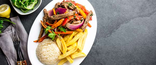 A meat dish of beef tenderloin with onion, chili and tomato A meat dish served with onion, chili and tomato