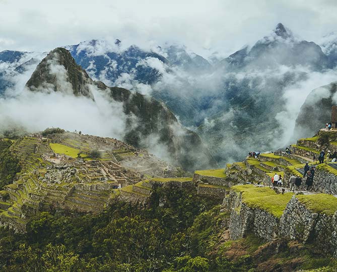 Adventure travel tourists explore Machu Picchu on holiday Explore Peru on holiday and see UNESCO World Heritage Site, Inca heritage, Ancient ruins
