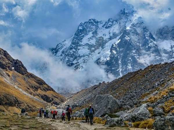 Group tour hiking through the Salkantay mountains in Peru Group tour in Peru. Adventure travel tourists hiking on a group tour of Peru through the salkantay mountain range