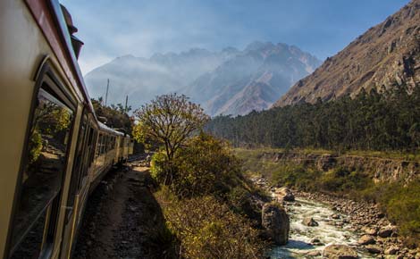 Peru group tour travellers look on as the train pazses through the mountains and rivers near Machu Picchu ruins