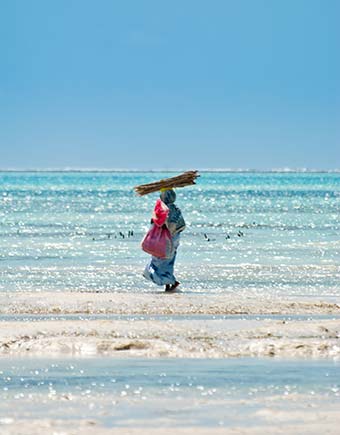 Travel Advice for Zanzibar, Tanzania tanzanian woman walking on the beach in zanzibar