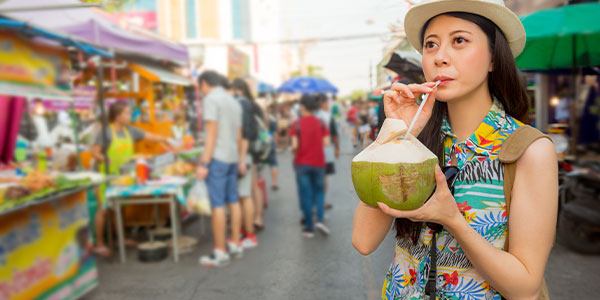A traveller sipping coconut water in Thailand A traveller sipping on fresh coconut water in a market in Bangkok