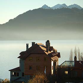 house on the misty lake with mountains in argentina in the background