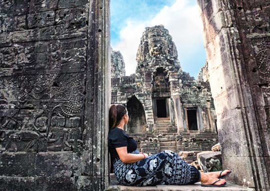 young woman traveler discovers the historic ancient ruin of Angkor Wat
