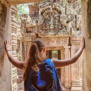 female solo traveller explores ancient ruins in cambodia whilst on a group holiday trip