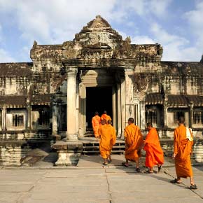 Cambodian monks walking through a temple door way for morning prayers