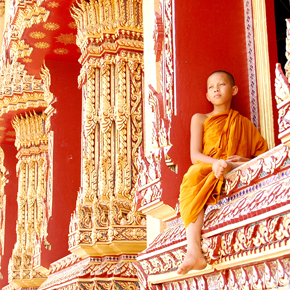 A young monk sits in a temple window a young monk sits on a temple window looking onto the landscape of cambodia