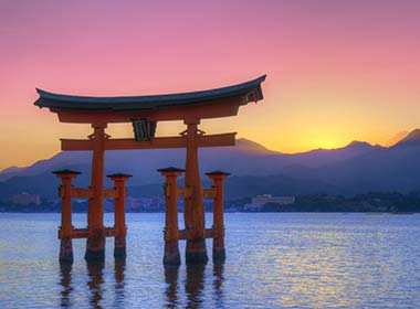 the floating otorii gate at miyajima in japan as the sun sets over the lake