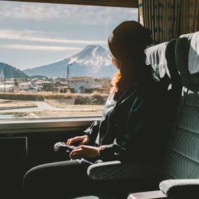Female traveler passes Mt. Fuji on the train female solo tourist on the train passing mount fuji in the distance