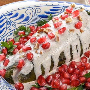 chiles en nogada chilis coated in cream sauce with pommegranate seeds