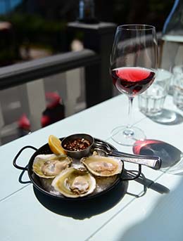 Knysna Oyster Festival, South Africa oysters in a black dish with a glass of wine on a white table for the knysna oyster festival