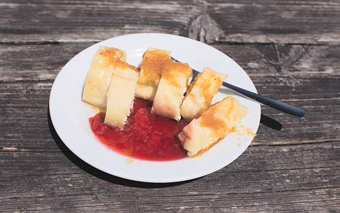 Traditional Slovene Struklji with strawberry jam an white plate, wood as background. Struklji are made of cooked dough and cottage cheese and can be served as side dish or dessert best foods to eat in eastern europe is struklji in ljubljana slovenia europe