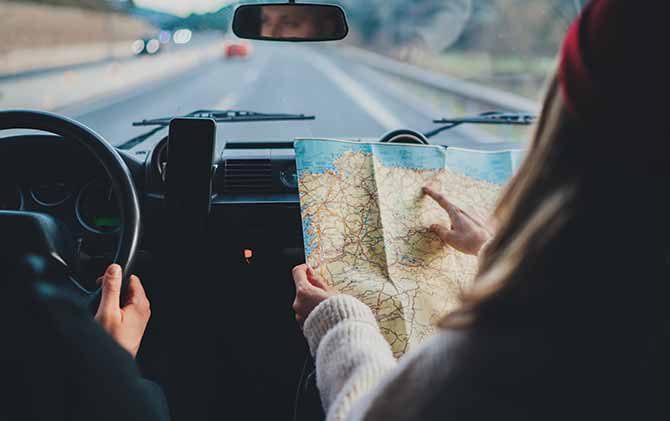 getting around europe by car with a man driving and a woman reading a map
