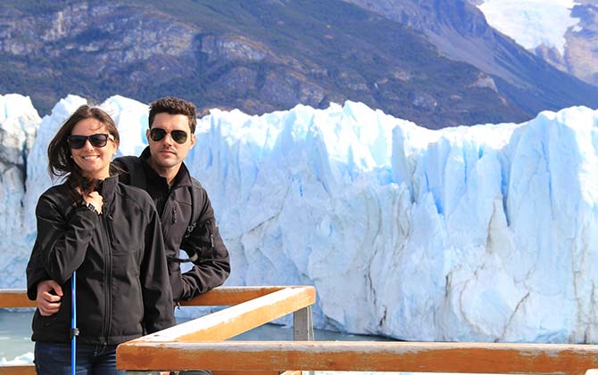 A travelling couple posing on the bridge platform overlooking the Perito Moreno Glacier in Los Glaciares National Park in Patagonia