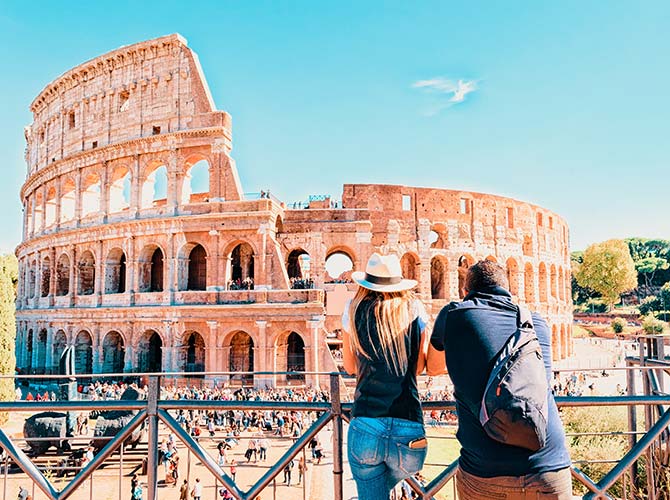 a young couple looking to the colosseum in Italy, one of the 7 new wonders of the world