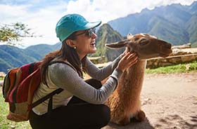 Woman smiling and stroking a llama on a trek to Machu Picchu in Peru