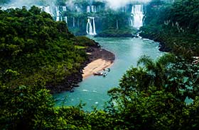 Iguazu Falls in Brazil with clear blue water and green shrubbery and waterfalls