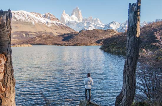 solo traveller standing infront of lake capri in patagonia after hiking a trail to view the stunning mount fitz roy
