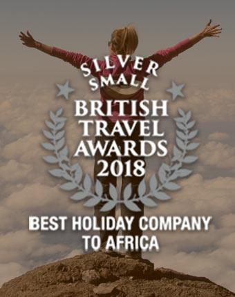 Tucan Travel wins Silver at the British Travel Awards 2018 for Best Holiday Company to Africa - background photo single traveller above the clouds after conquereing the solo trip Kili Hike Tucan Travel winning silver at the British Travel Awards 2018 for best holiday company to Africa - Single touirst has conquered her hike up mount Kilimanjaro whilst on her solo trip in Tanzania with Tucan Travel