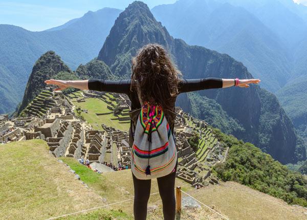 single traveler in awe of her surroundings infront of ancient Inca ruins at Machu Picchu in Peru